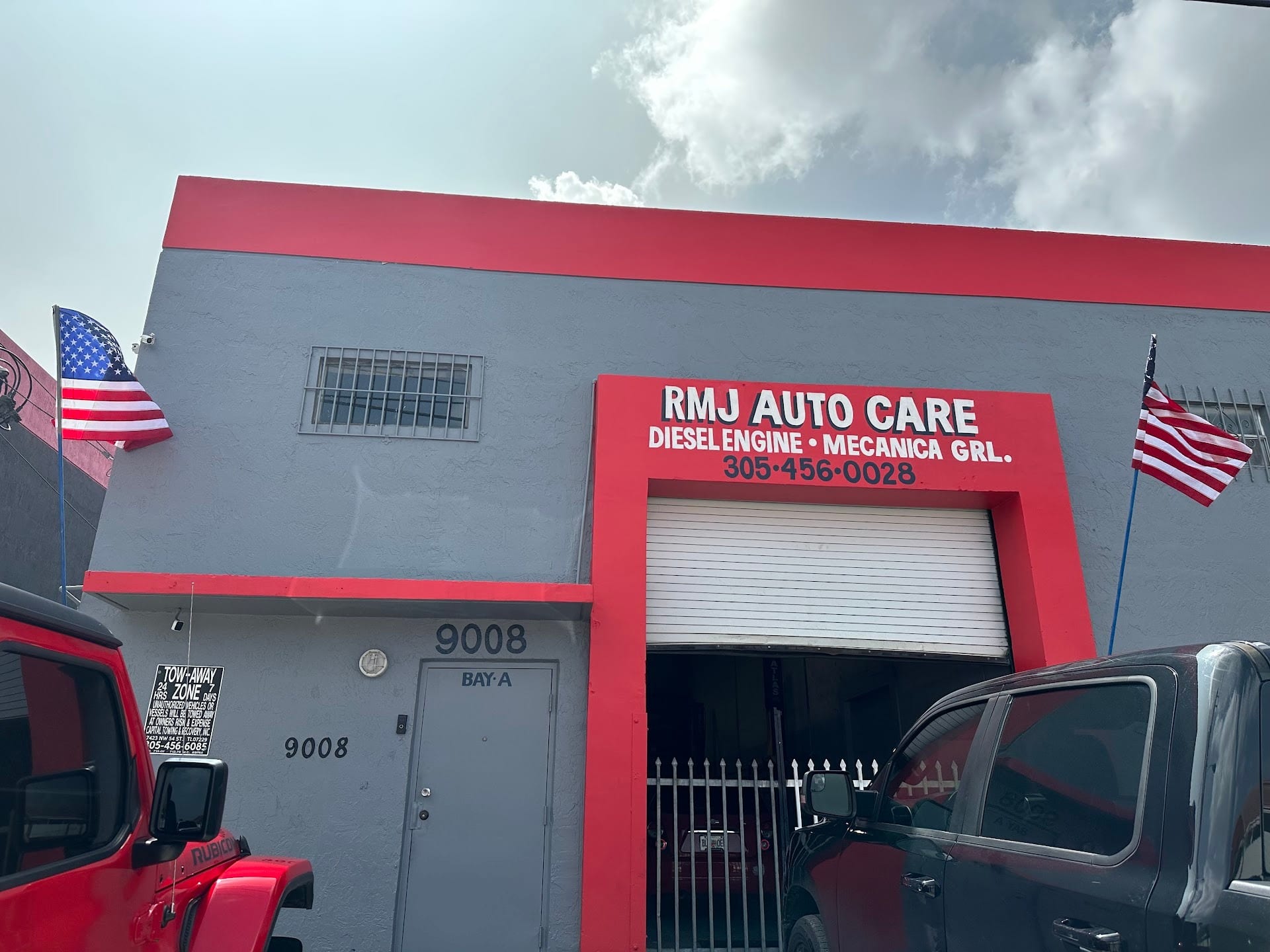 RMJ Auto Care storefront on NW 119th St: the red bay-door frame with the Diesel Engine and Mecánica General sign